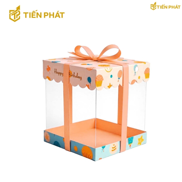 Hộp bánh kem trong suốt, màu cam, họa tiết bong bóng và chữ "Happy Birthday"